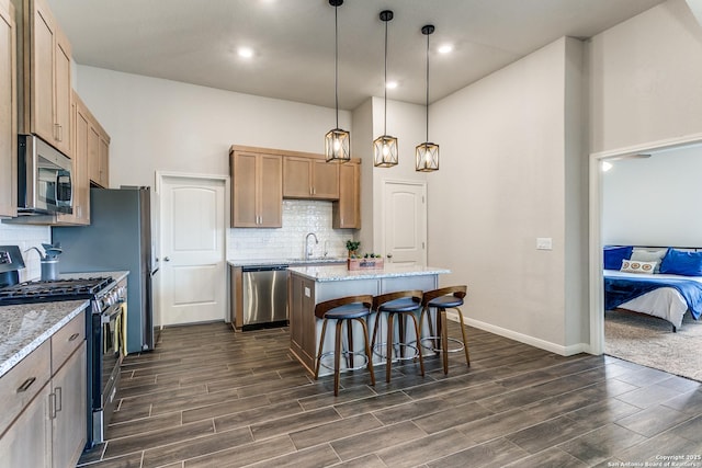 kitchen featuring wood tiled floor, a center island, a kitchen breakfast bar, and stainless steel appliances