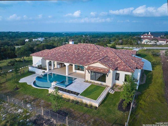 view of swimming pool with a patio, a fenced backyard, a pool with connected hot tub, and a lawn