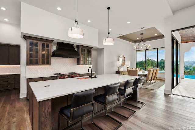 kitchen featuring custom range hood, light countertops, backsplash, visible vents, and a sink