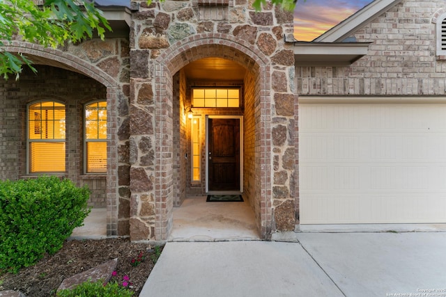 14047 Pikesdale, San Antonio, TX 78253 - exterior entry at dusk featuring an attached garage, driveway, and stone siding