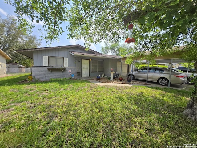 5346 San Benito, San Antonio, TX 78228 - view of front facade featuring fence, a front yard, brick siding, board and batten siding, and a carport