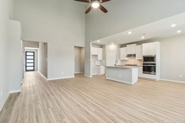 18107 Ansley, San Antonio, TX 78247 - kitchen with stainless steel appliances, under cabinet range hood, light wood-type flooring, and white cabinetry