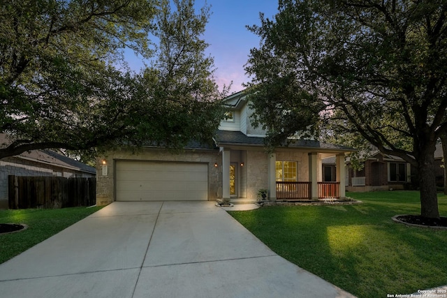 view of front of property with a front yard, fence, stone siding, an attached garage, and driveway