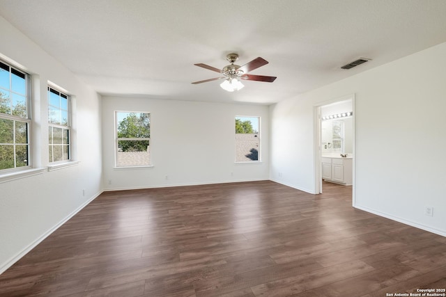 unfurnished room with a healthy amount of sunlight, dark wood-style flooring, ceiling fan, and visible vents