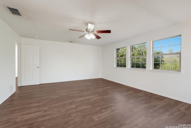 empty room with ceiling fan, visible vents, and dark wood-style flooring