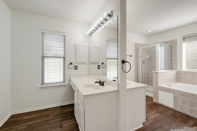 full bath with baseboards, a bath, vanity, wood finished floors, and a stall shower