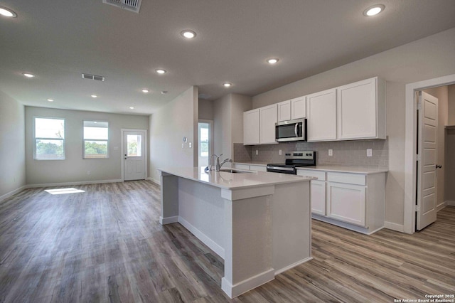 kitchen with visible vents, appliances with stainless steel finishes, a sink, open floor plan, and backsplash