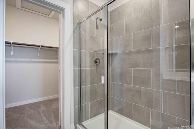 full bath with a walk in closet, baseboards, and a stall shower