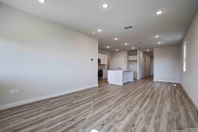 unfurnished living room with light wood-style floors, baseboards, visible vents, and recessed lighting