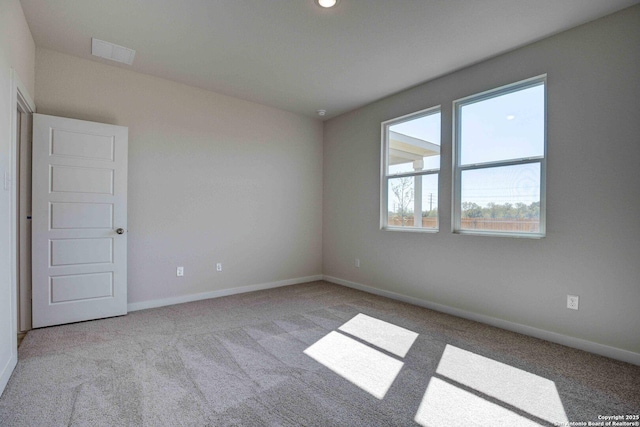 carpeted spare room with visible vents and baseboards