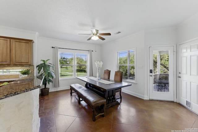 dining space with visible vents, ceiling fan, dark tile patterned flooring, and a healthy amount of sunlight