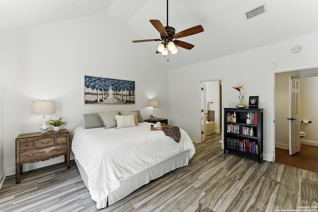 bedroom featuring ensuite bath, visible vents, baseboards, and wood finished floors