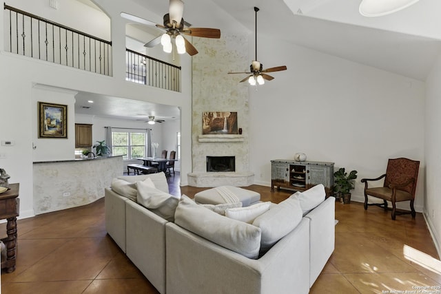 tiled living room with high vaulted ceiling, ceiling fan, baseboards, and a fireplace