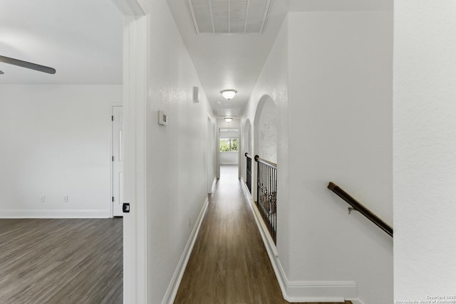 corridor featuring an upstairs landing, visible vents, baseboards, and wood finished floors