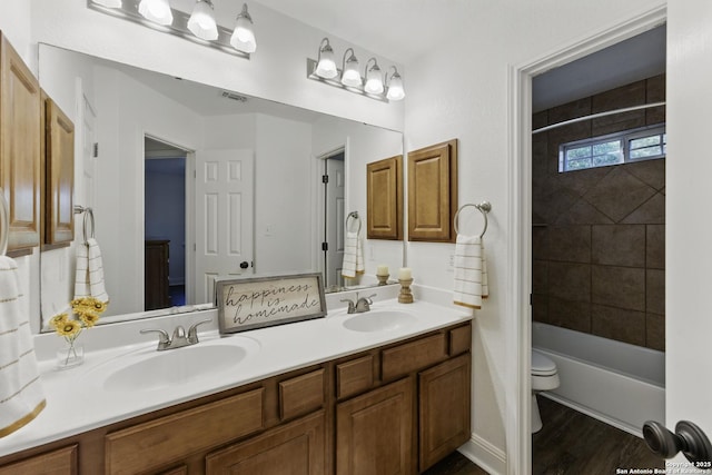 bathroom with double vanity, visible vents, a sink, and toilet