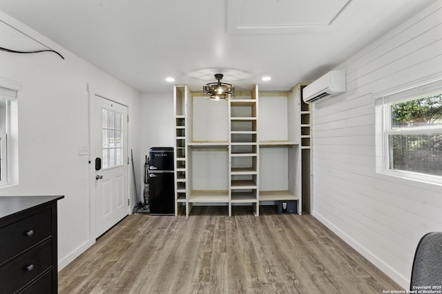 walk in closet featuring a wall mounted AC and light wood-type flooring