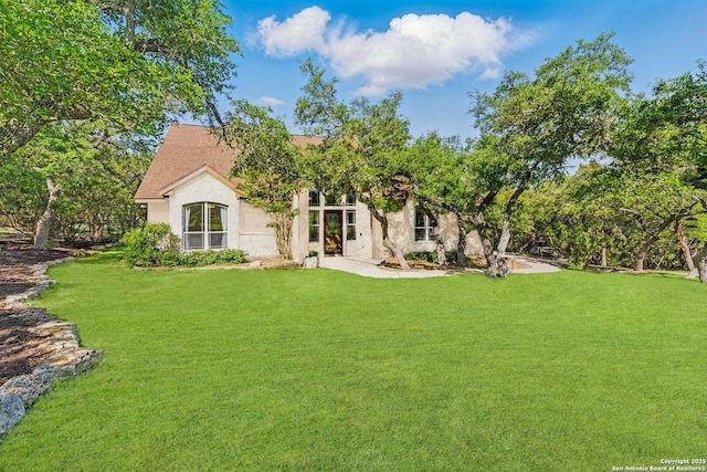 rear view of house with stucco siding and a lawn