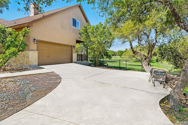 view of home's exterior featuring a chimney, driveway, stucco siding, and fence