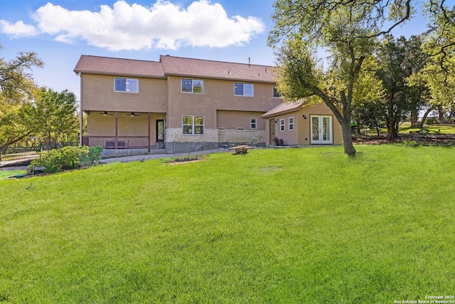 rear view of property featuring a yard, french doors, fence, and stucco siding