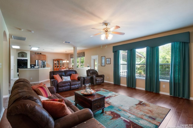 living room featuring ceiling fan with notable chandelier, wood finished floors, baseboards, and visible vents