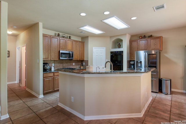 kitchen featuring dark stone countertops, light tile patterned floors, visible vents, decorative backsplash, and appliances with stainless steel finishes