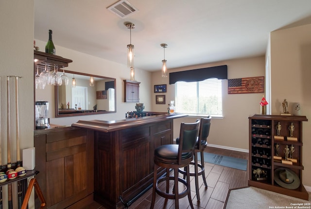 bar with visible vents, baseboards, a dry bar, wood tiled floor, and pendant lighting