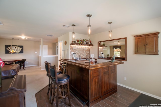 bar with wet bar, baseboards, visible vents, and hanging light fixtures