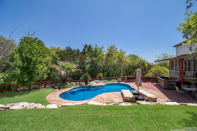 pool featuring a wooden deck, a fenced backyard, and a lawn