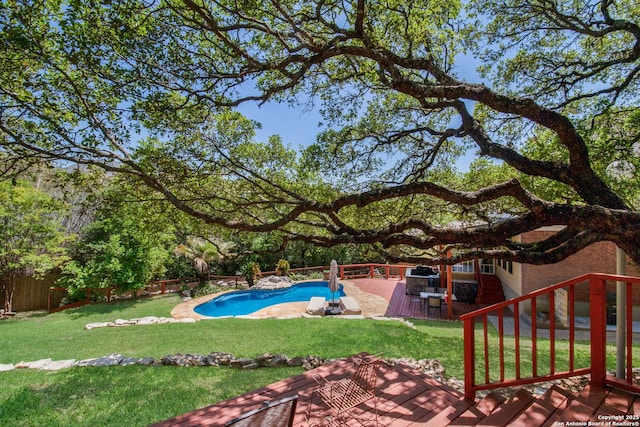 outdoor pool with a yard, a deck, and a fenced backyard