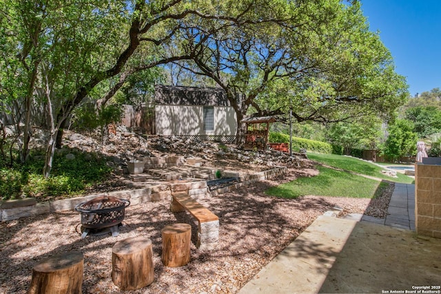 view of yard with an outdoor fire pit, an outbuilding, a storage shed, and fence