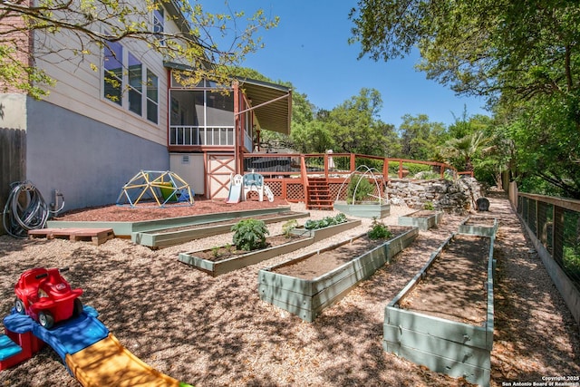view of yard with a sunroom, a deck, fence, and a vegetable garden