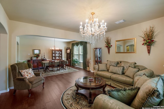 living area with arched walkways, visible vents, wood finished floors, baseboards, and a notable chandelier