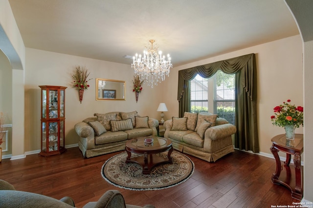 living area featuring arched walkways, wood-type flooring, a notable chandelier, and baseboards