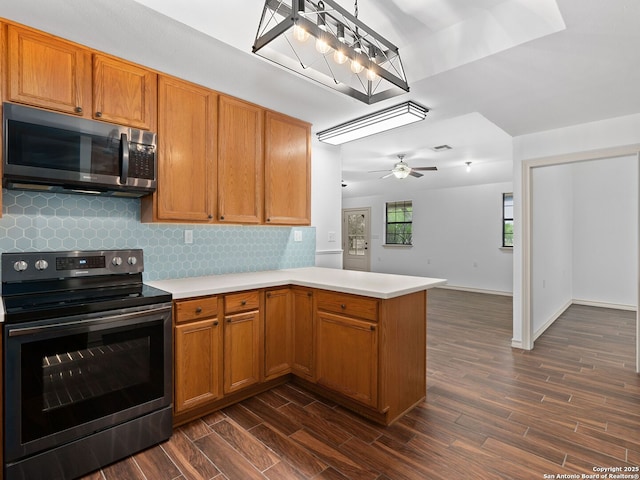 601 Wildflower Dr, Lytle, TX 78052 - kitchen featuring dark wood finished floors, electric range, a peninsula, light countertops, and decorative backsplash