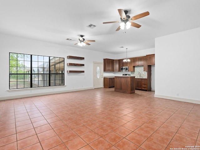 601 Wildflower Dr, Lytle, TX 78052 - unfurnished living room with baseboards, light tile patterned floors, visible vents, ceiling fan, and a sink