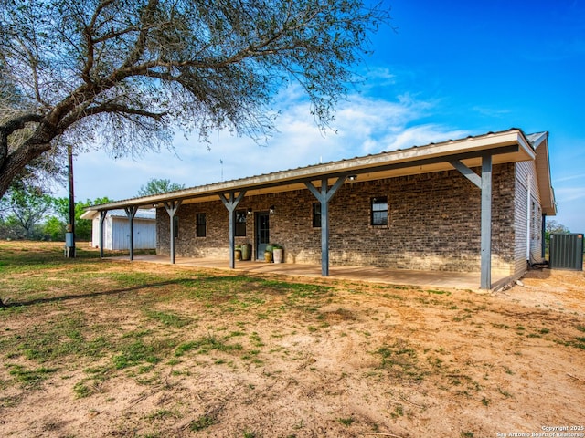 601 Wildflower Dr, Lytle, TX 78052 - back of property with central air condition unit, a patio, fence, and brick siding