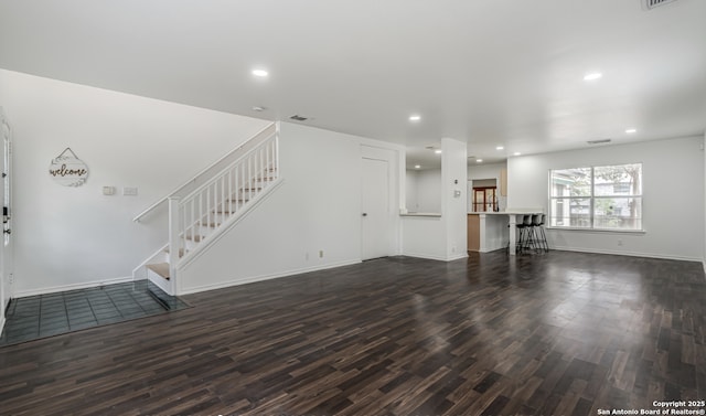 unfurnished living room with wood finished floors, stairs, recessed lighting, and baseboards