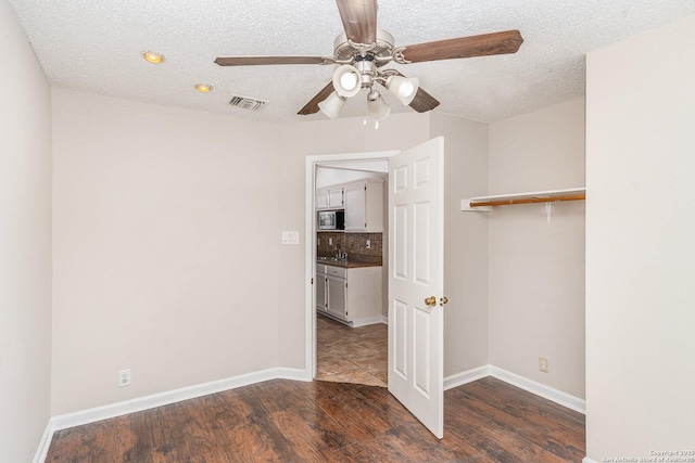 empty room with baseboards, a ceiling fan, visible vents, a sink, and wood finished floors