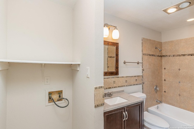 bathroom with vanity, tile walls, toilet, and shower / washtub combination