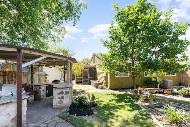 view of yard with an outbuilding, fence, cooling unit, and area for grilling