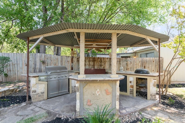 view of patio featuring grilling area, a gazebo, fence, and exterior kitchen