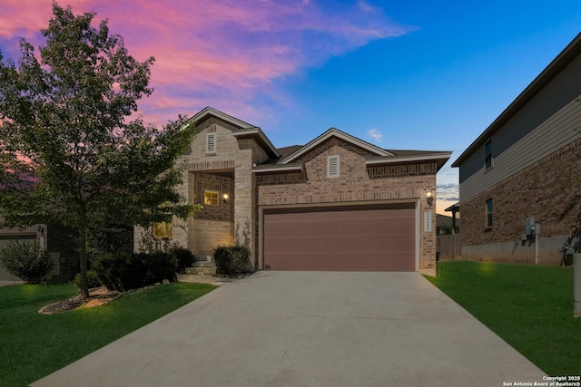 traditional-style home featuring stone siding, a front lawn, brick siding, an attached garage, and driveway