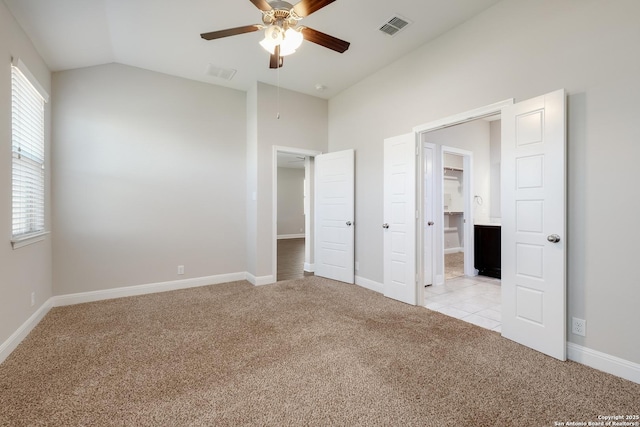 unfurnished bedroom with visible vents, baseboards, light colored carpet, and vaulted ceiling