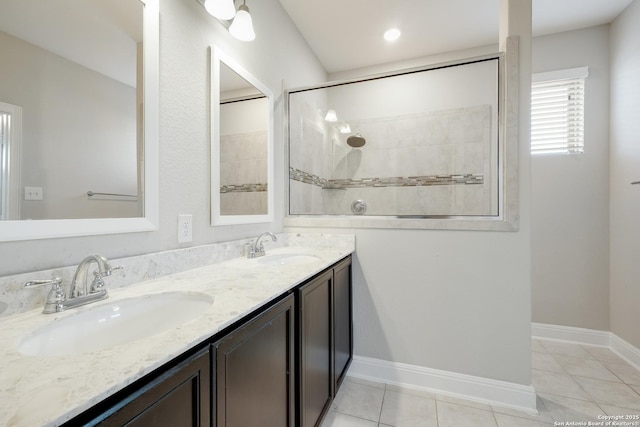 bathroom with tile patterned floors, double vanity, a sink, and tiled shower