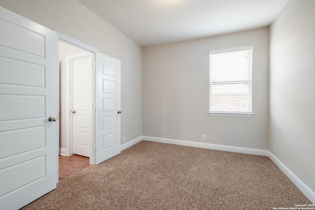 unfurnished bedroom featuring baseboards and light colored carpet