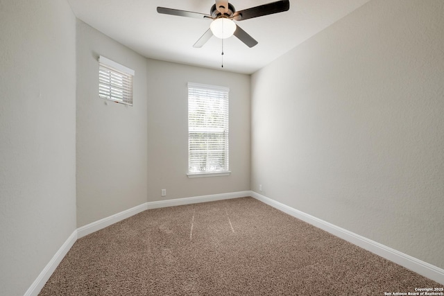 carpeted spare room featuring baseboards and a ceiling fan