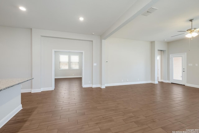 unfurnished living room with visible vents, ceiling fan, wood finished floors, and baseboards