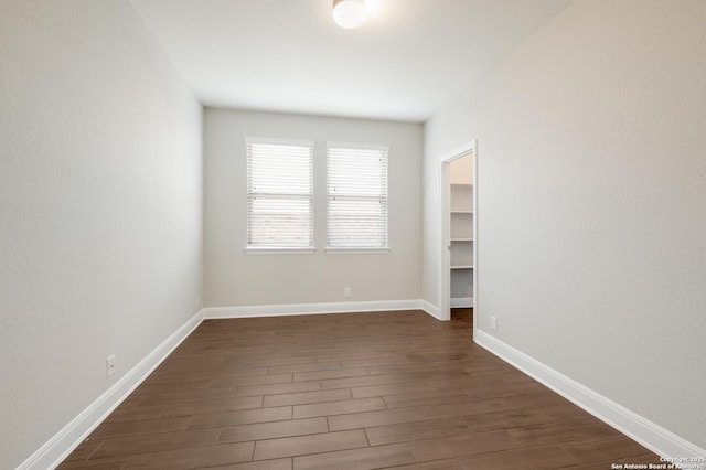 unfurnished room featuring baseboards and dark wood finished floors