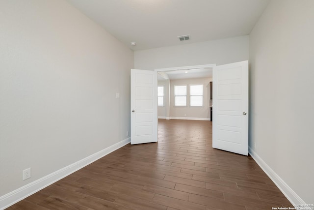 spare room featuring visible vents, baseboards, and dark wood-style floors
