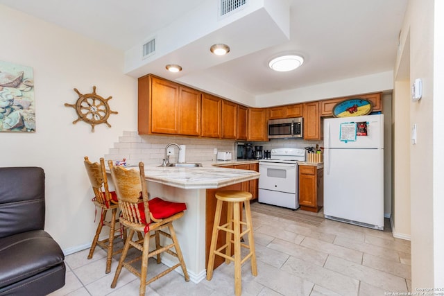71 W Nassau Unit 302, Rockport, TX 78382 - kitchen with white appliances, tasteful backsplash, a peninsula, a sink, and a breakfast bar area